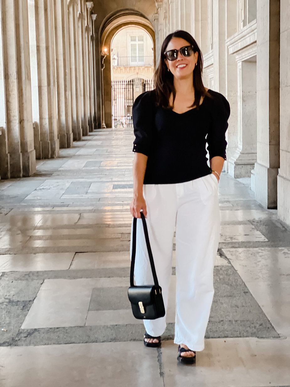 White pants with black bash sweater, leather black handbag, and sandals