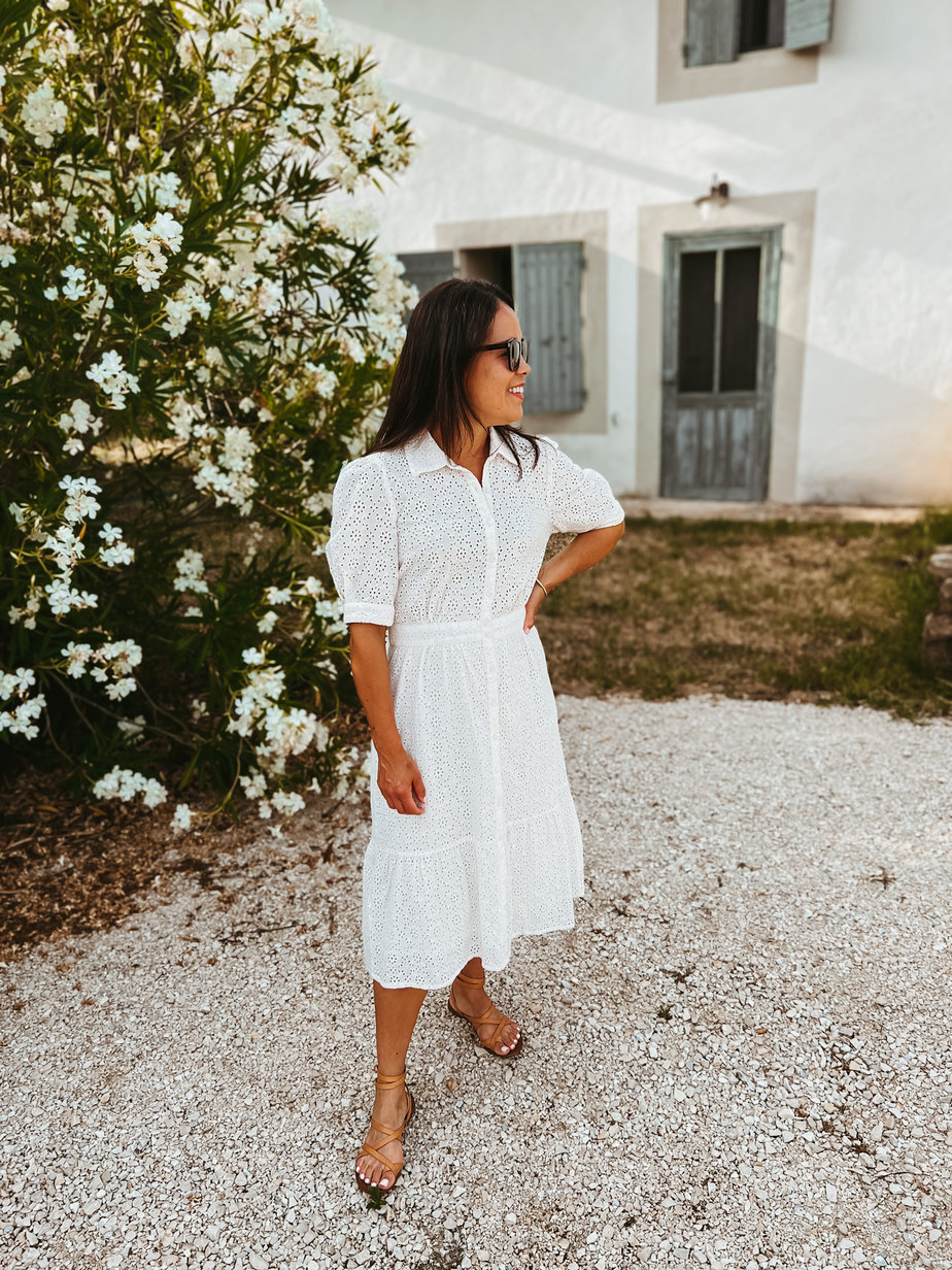wearing white dress with sandals standing in front of white tree