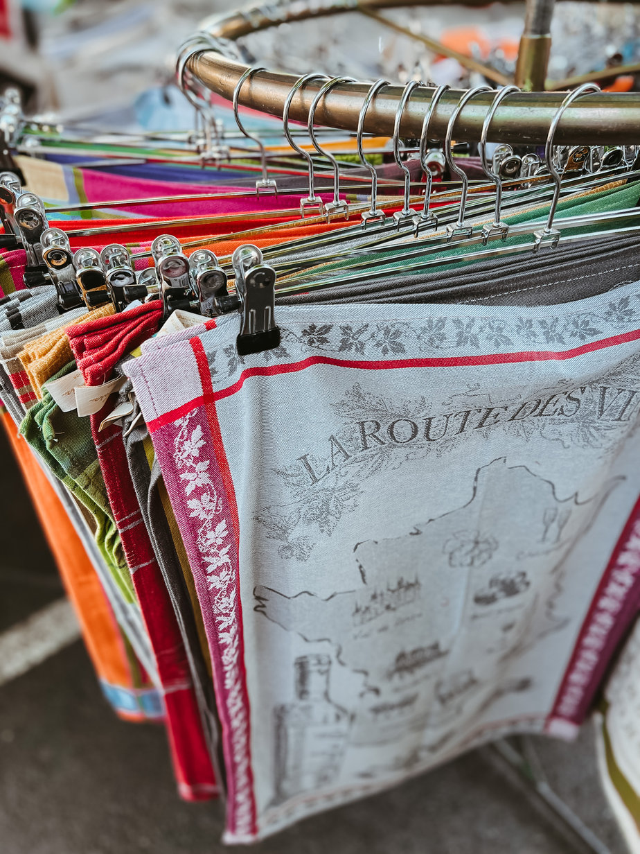 FRENCH TEA TOWLS FRENCH TEA TOWLS HANGING ON A RACK AT A FLEA MARKET IN FRANCE.
