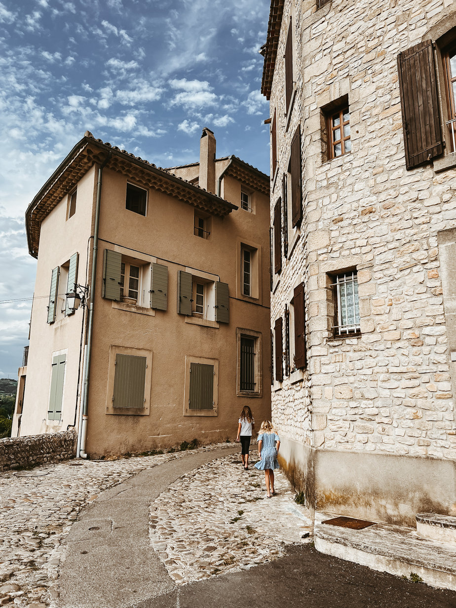 Kids running up a cobble stone street in village in Provence.