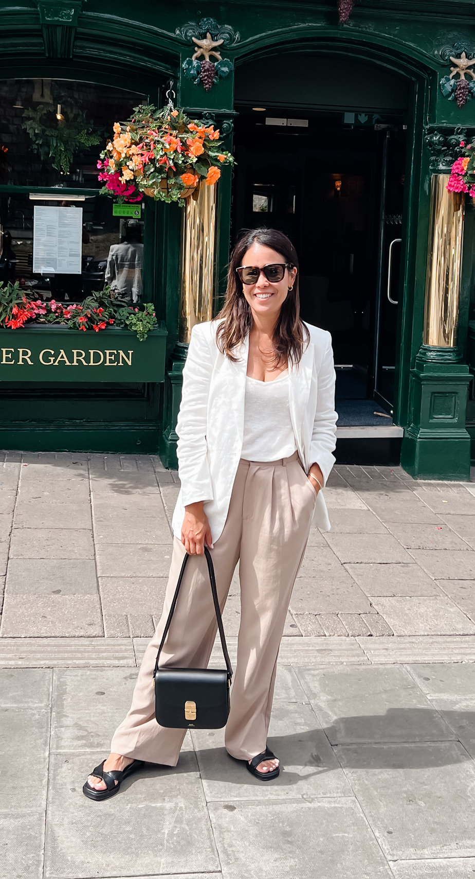 wearing white blazer with tan trousers and black sandals outside pub in England