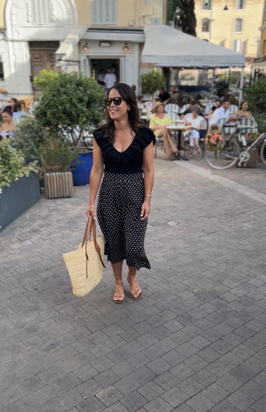 wearing black polka dot skirt, with sandals, and black bodysuit in Marseilles