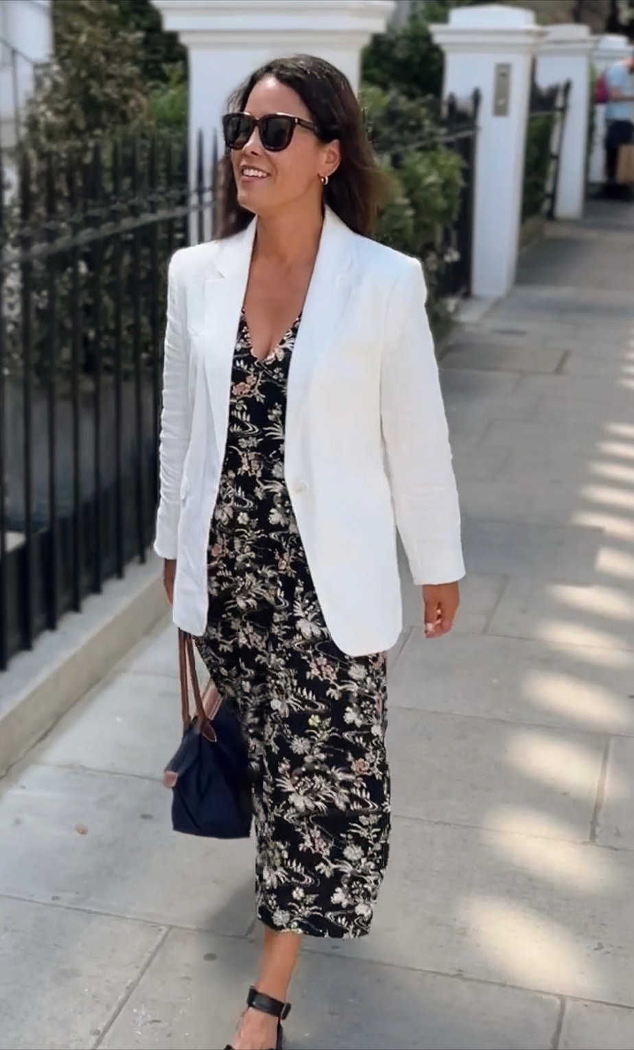 White blazer with dress, navy bag, sandals walking