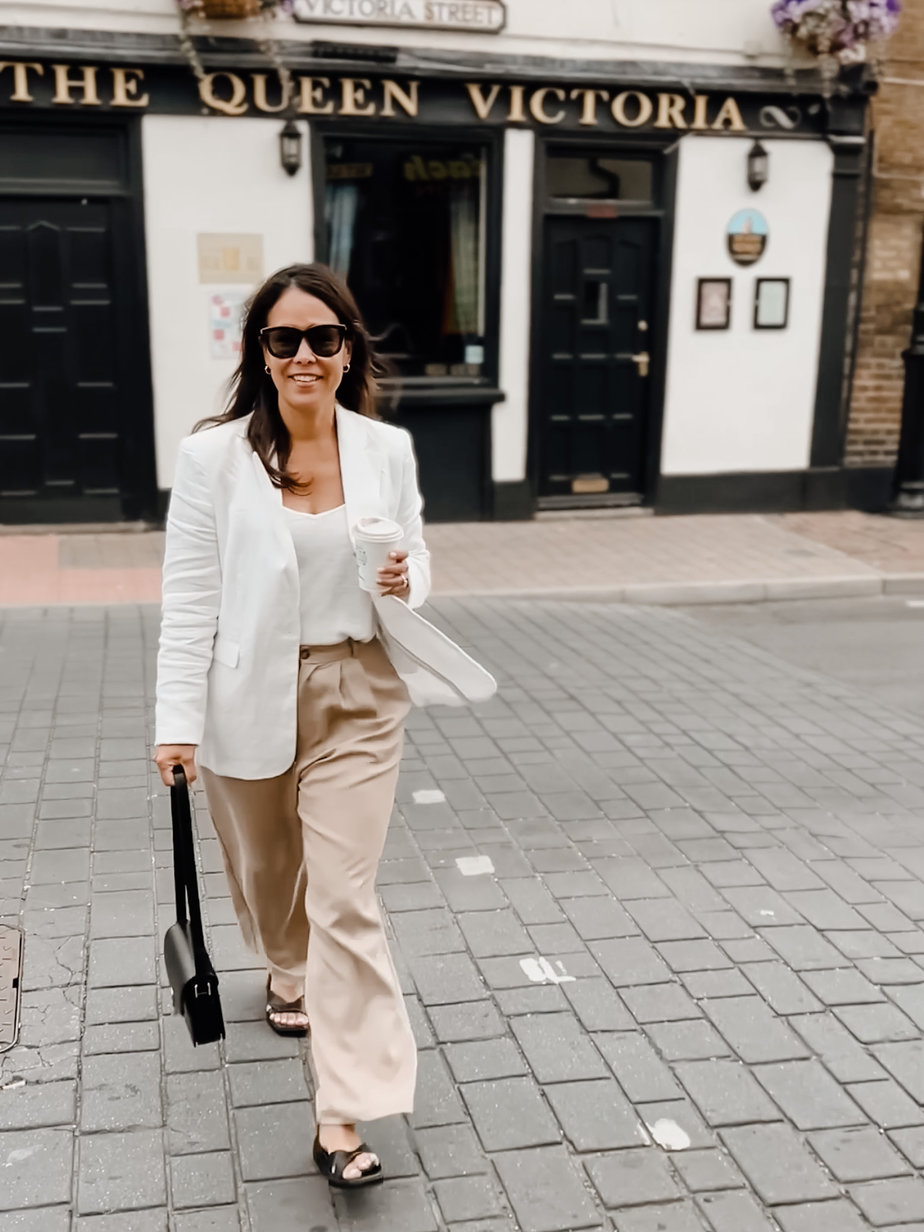 Wearing White Blazer With Tan Trousers and Black Sandals in front of put in England
