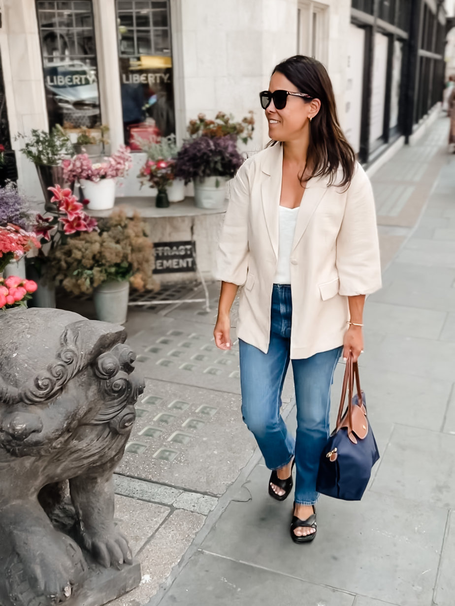 Wearing tan blazer with black sandals, jeans, navy bag in London