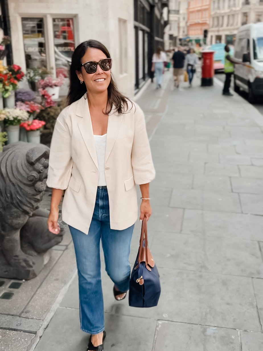 wearing tan blazer with denim, navy longchamp bag and sandals