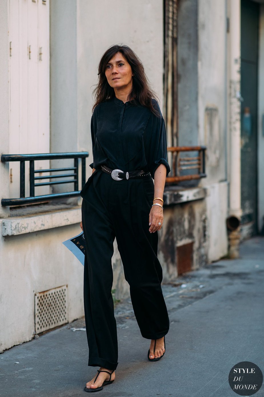 Emanuelle Alt wearing black pants, black silk top and black strappy sandals with a black braided belt walking down the street