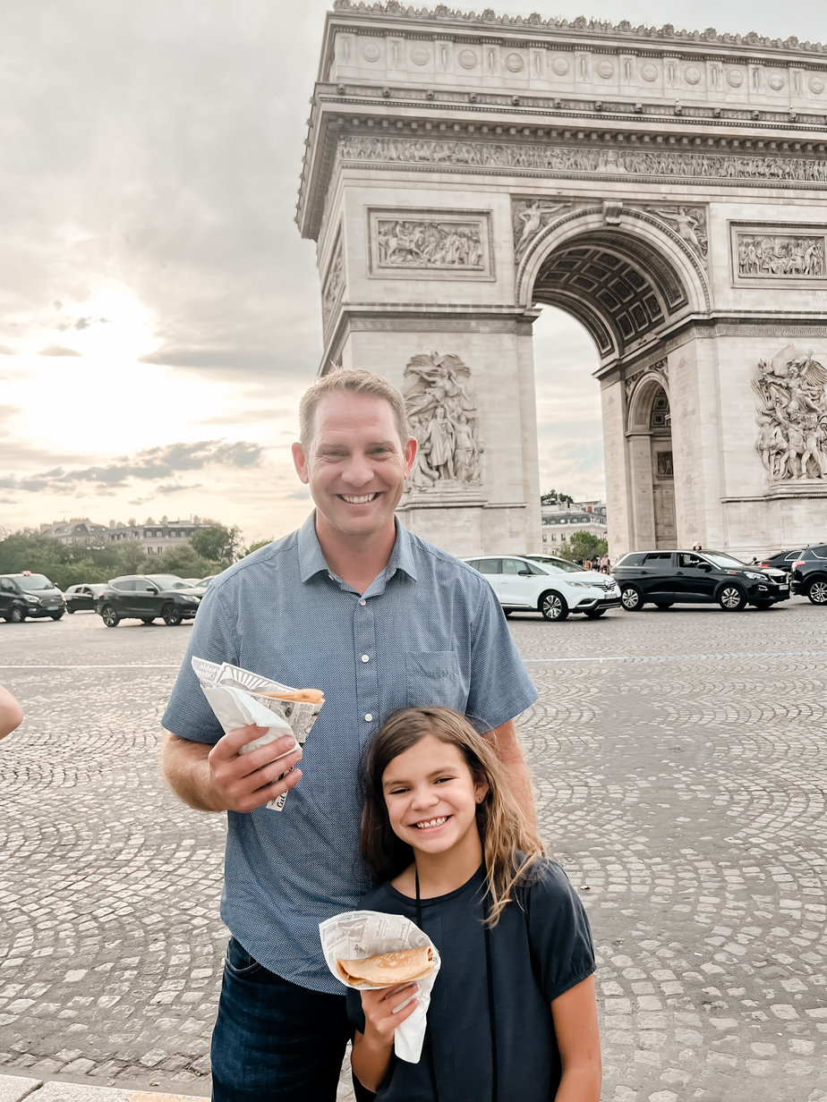 girl and dad with crepes in front of arc de triomphe 