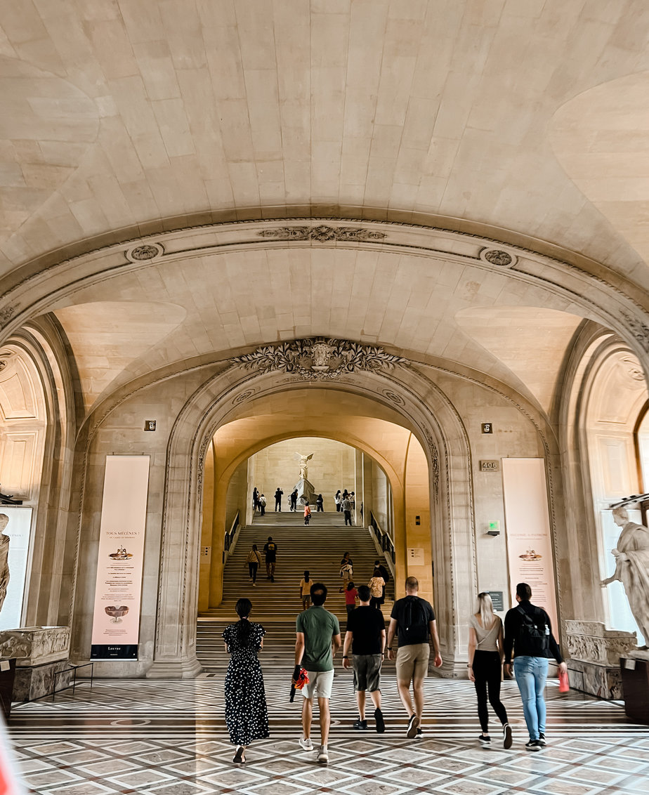 Inside archway at the louvre with people walking