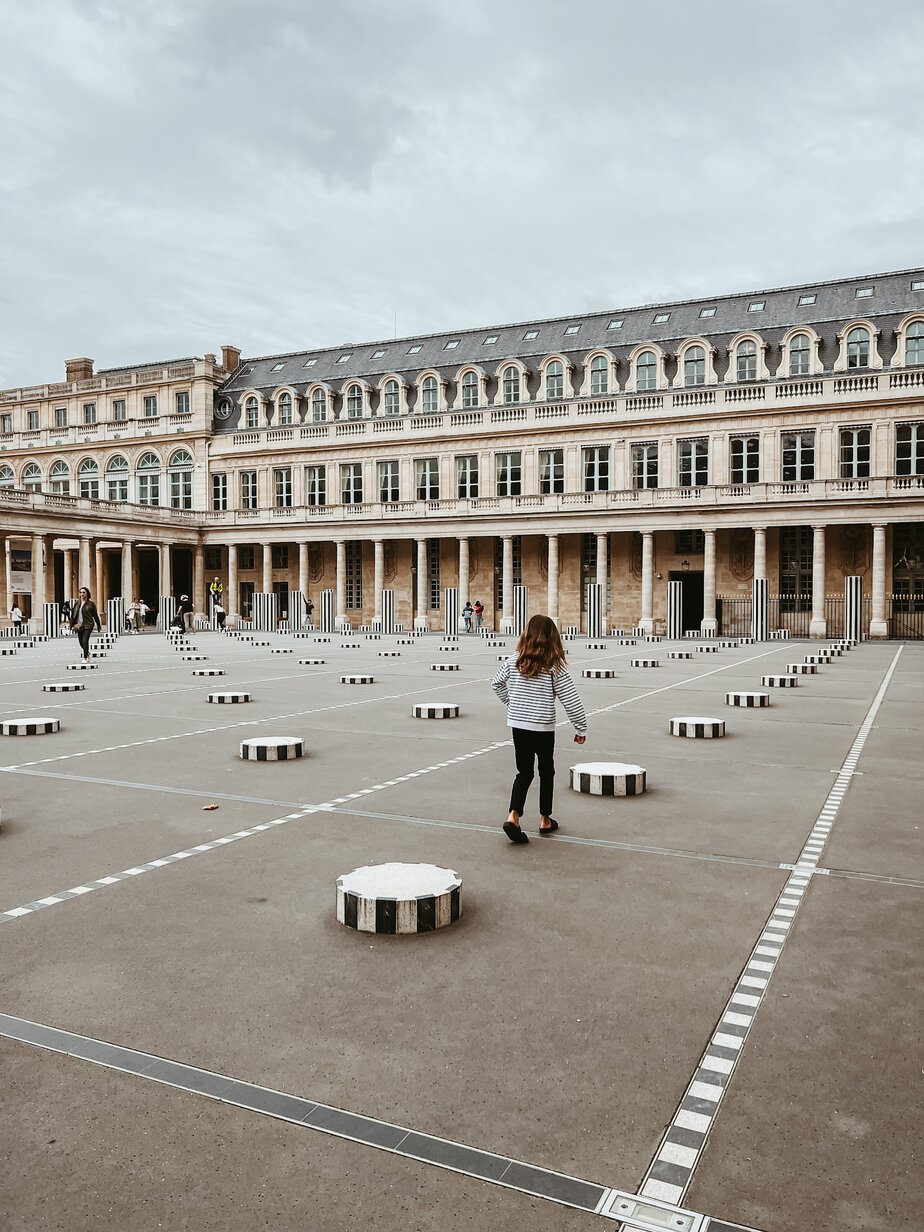 Little girl running through striped columns in Paris