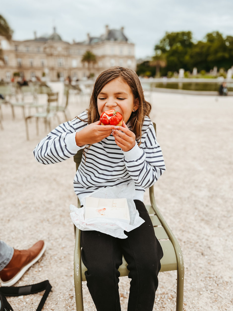 Girl eating a pastry in park in Paris