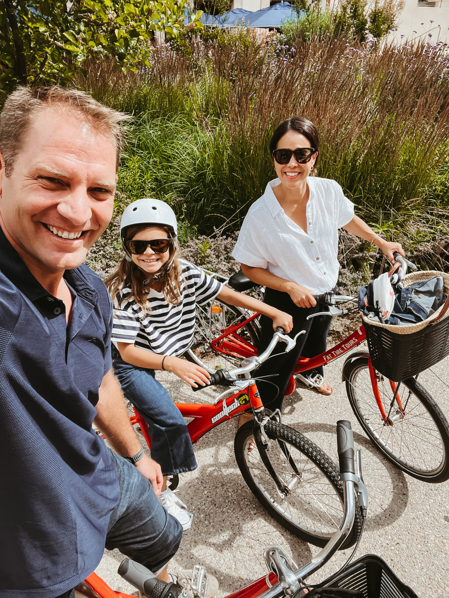 2 adults with a child wearing a bike helmet on bikes 
