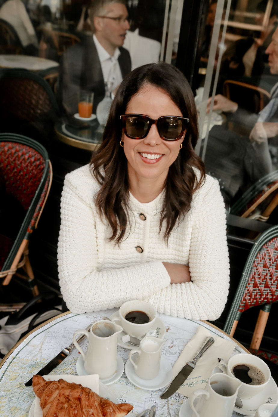 Fall Transition Jacket of white cardigan with sunglasses sitting at cafe de flore in Paris