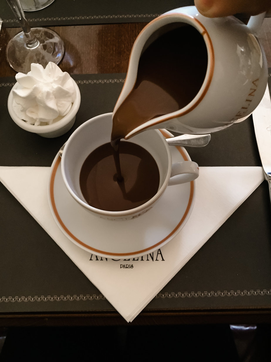 Pouring hot chocolate out of a white pot at Angelina's in Paris