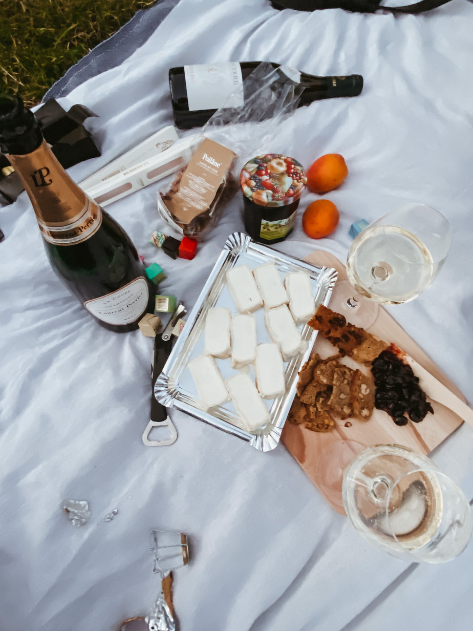 Champagne, cheese on a silver platter, fruit, jam, crackers on a white picnic blanket in Paris