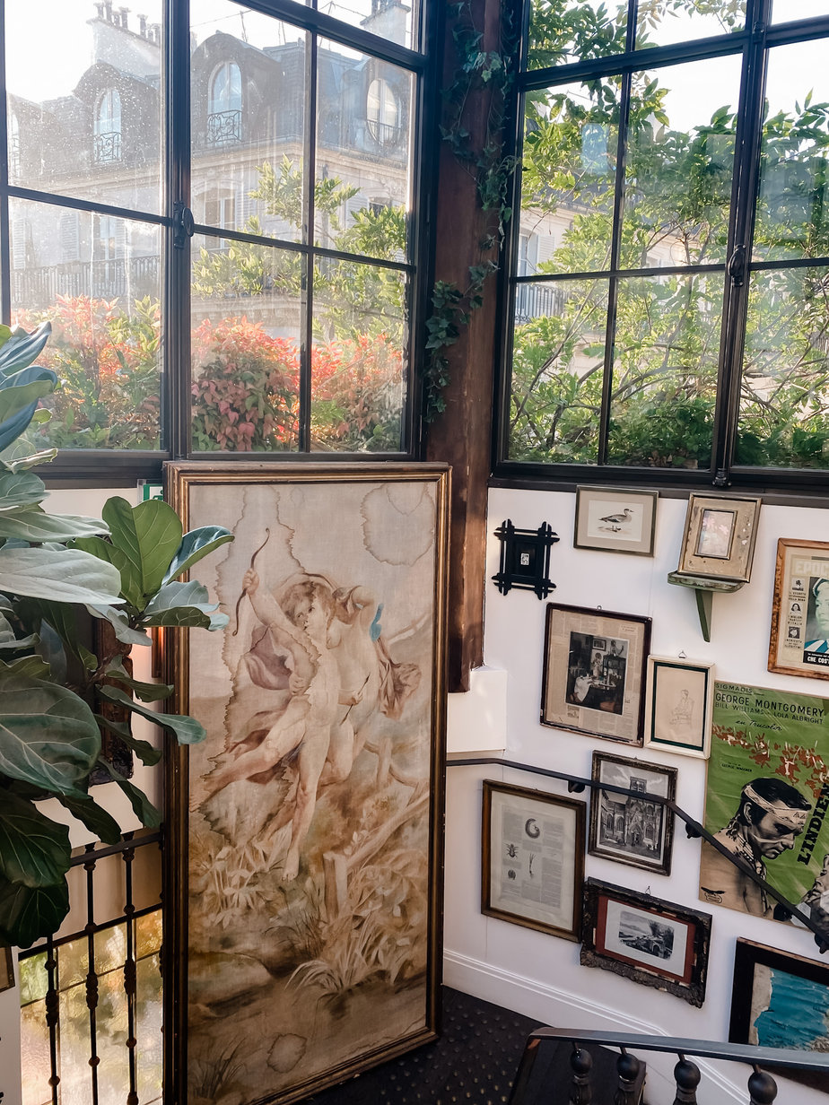 Gallery wall full of pictures with two large windows in the background