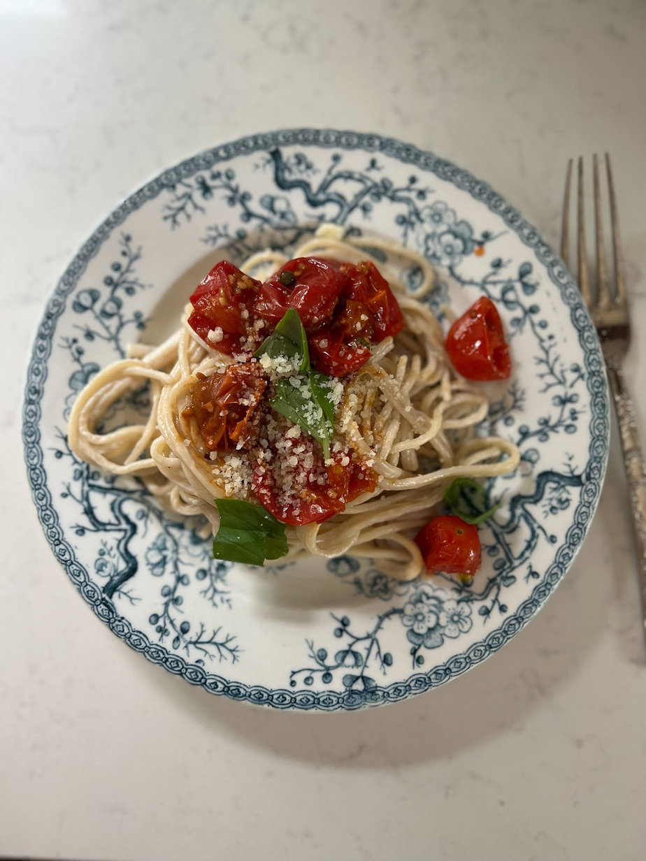 Pasta with tomatoes, basil, and noodles on a blue and white plate