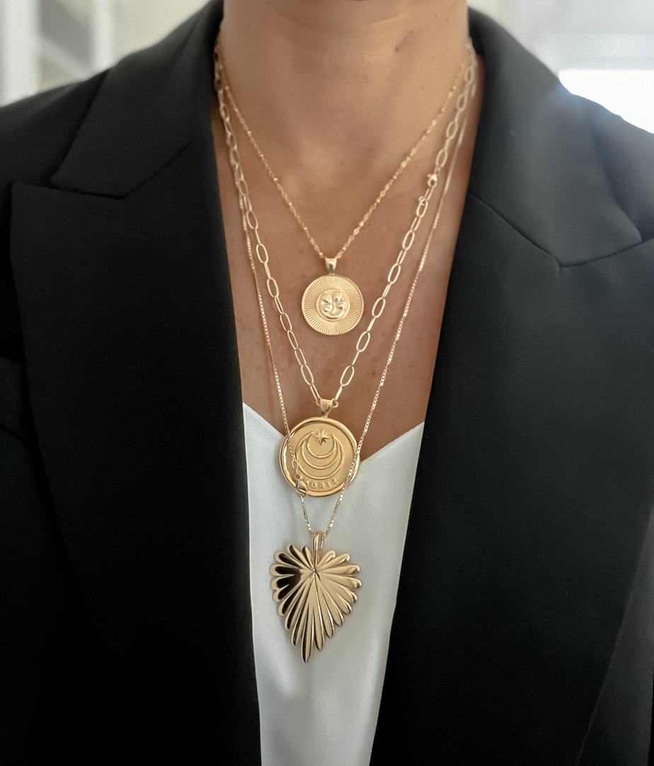Necklaces Layered on white tank top, 3 different gold necklaces.
