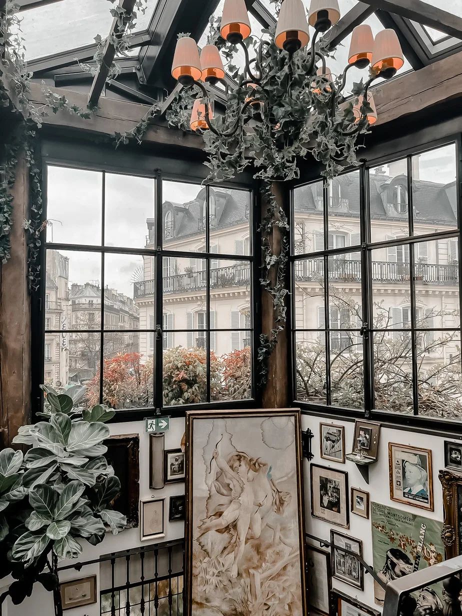 Big glass windows with paris facades in the background. Pictures hanging on a wall.