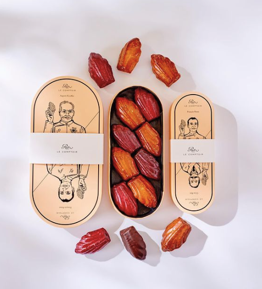 Madeleines sitting on a counter with 2 orange boxes from the Ritz Paris