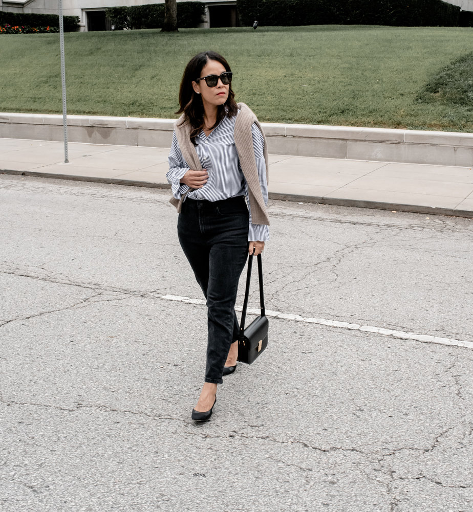 Woman walking across the street carrying black handbag.