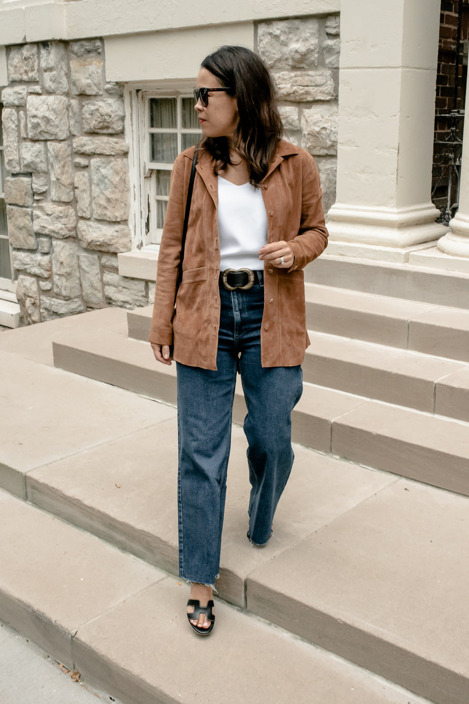 Lady wearing suede jacket with denim, white tank, and sandals for women over 40