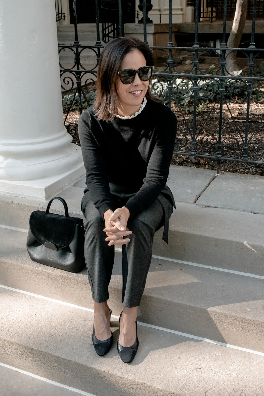 Lady wearing black sweater with white lace collar underneath and sitting on steps wearing sezane fall favorite.