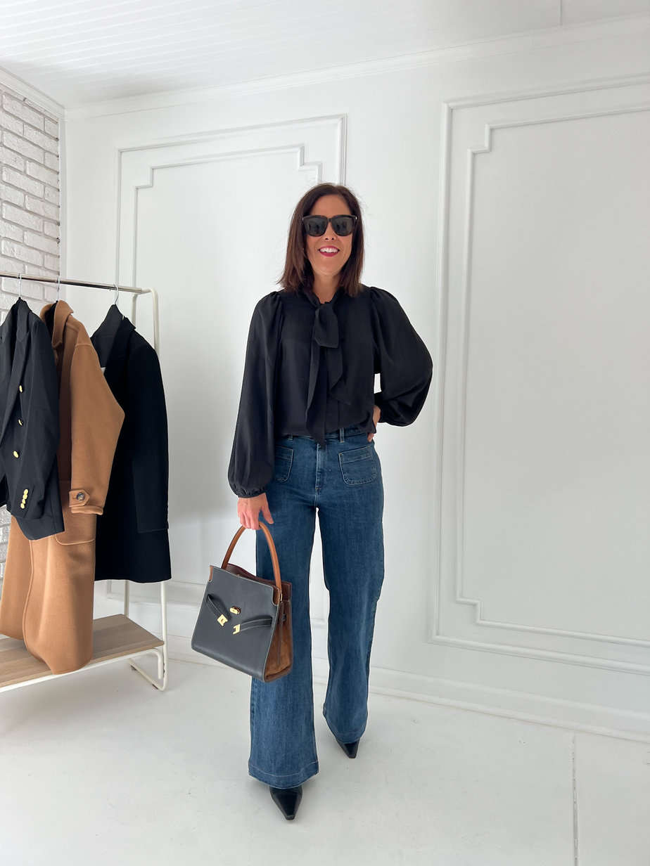 Wearing flare pocket jeans, black bow tie shirt, and handbag