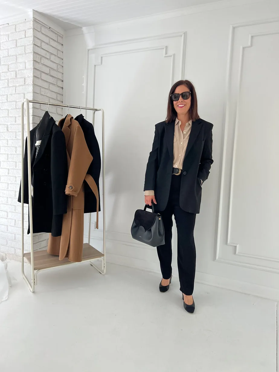 Woman wearing black blazer with black trousers, silk top, for a french look of the day.