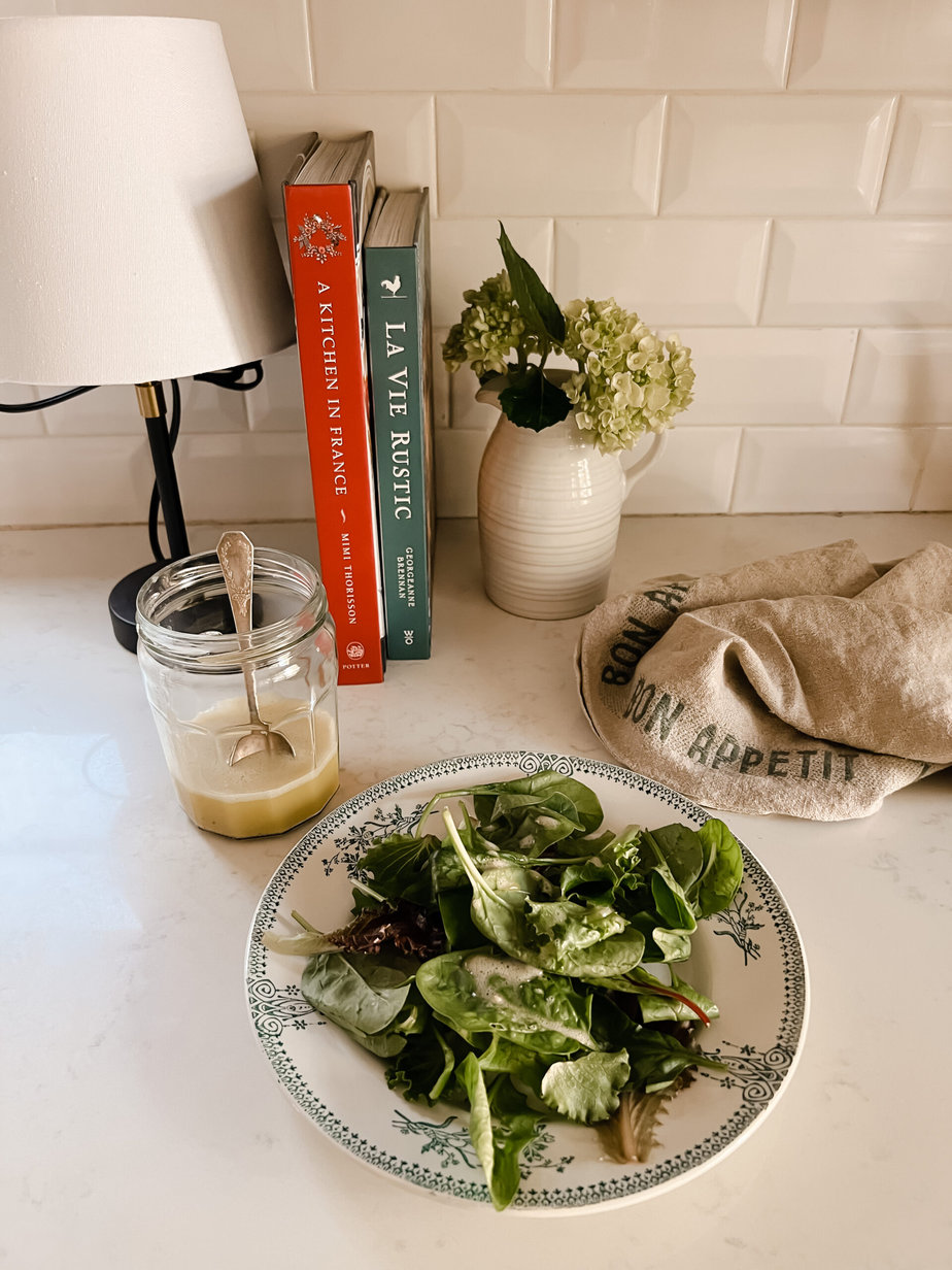 Green salad on a plate sitting on a counter for french fridays