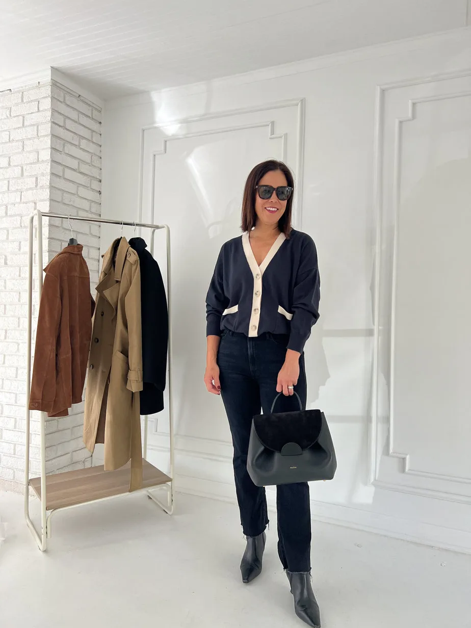 French look of navy cardigan with black denim, boots, and black handbag.