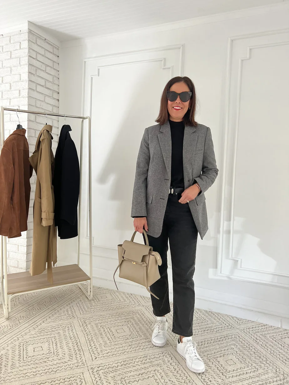 Woman wearing grey blazer with black denim, white sneakers and black turtleneck