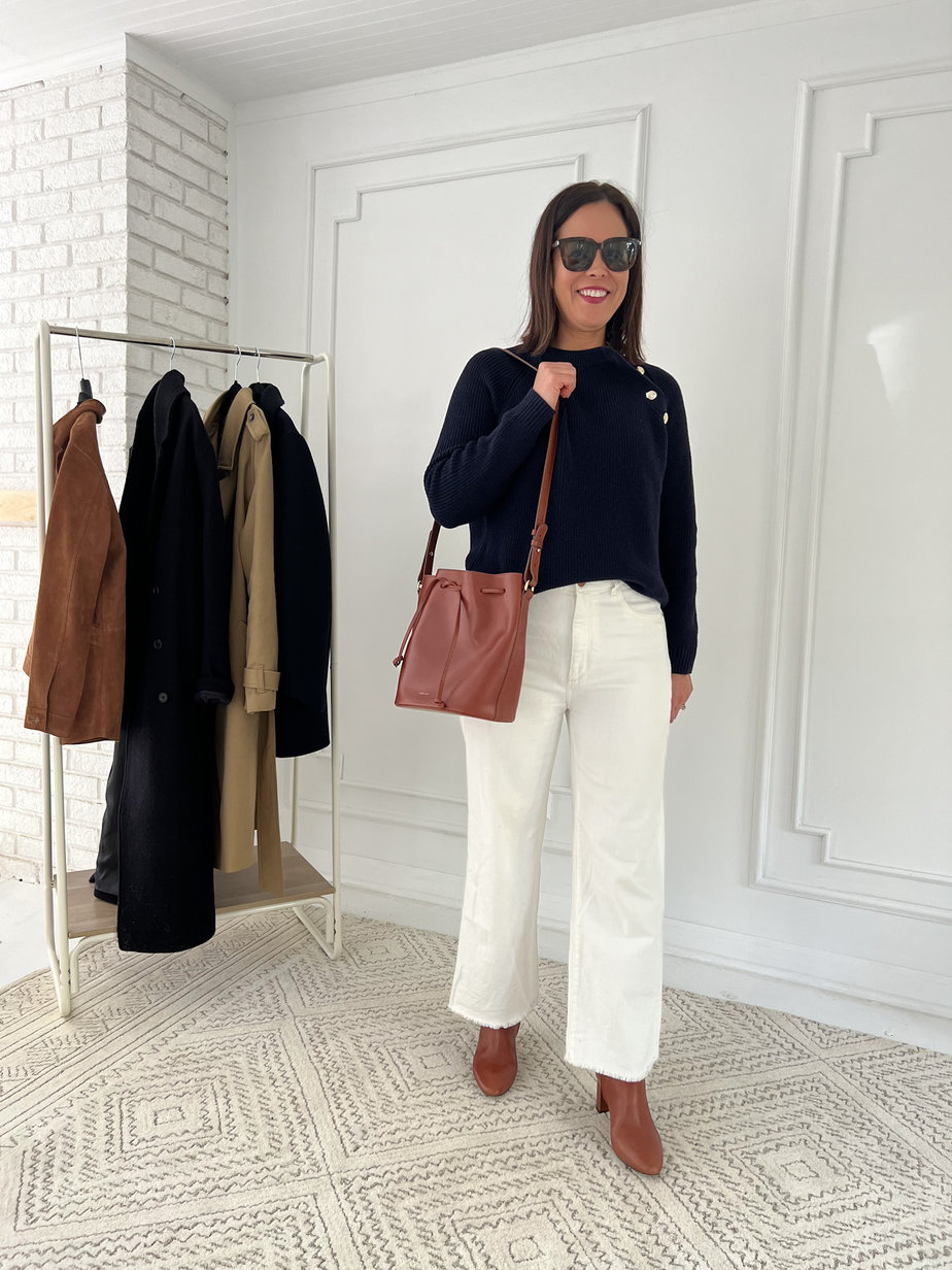 Wearing navy sweater with white denim, carmel boots, and brown leather handbag.