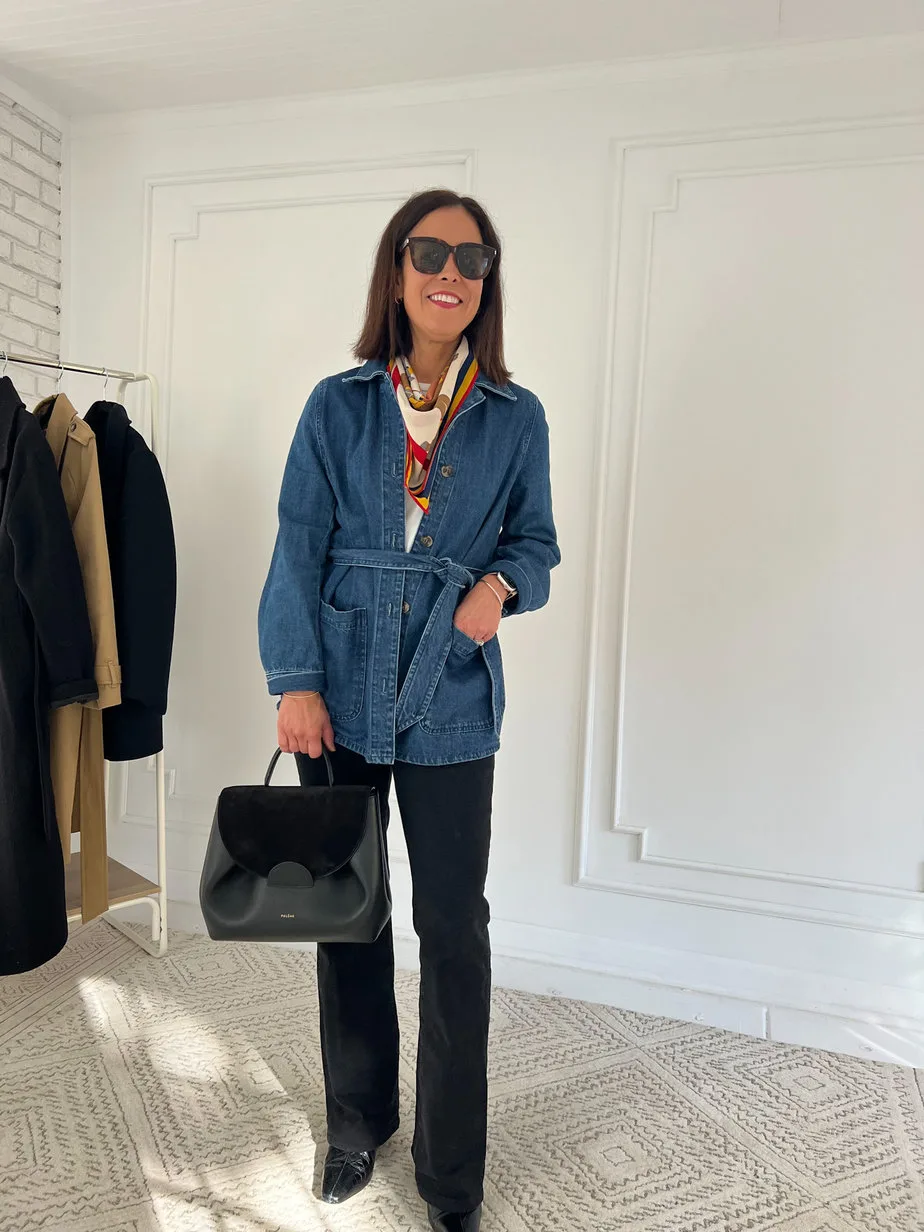 Lady wearing denim jacket, black jeans and carrying black handbag.