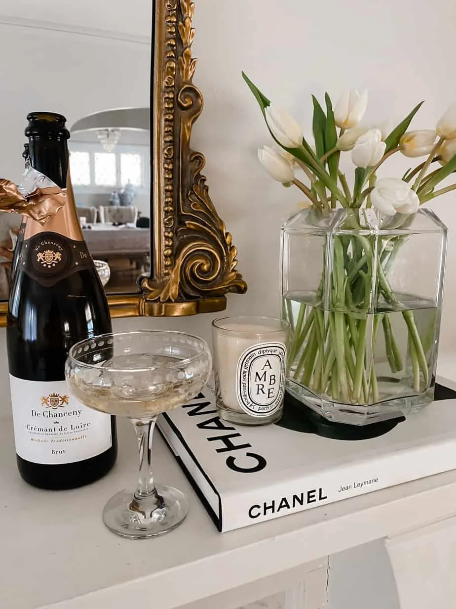 champagne bottle with glasses and vase with flowers sitting atop fireplace mantle.