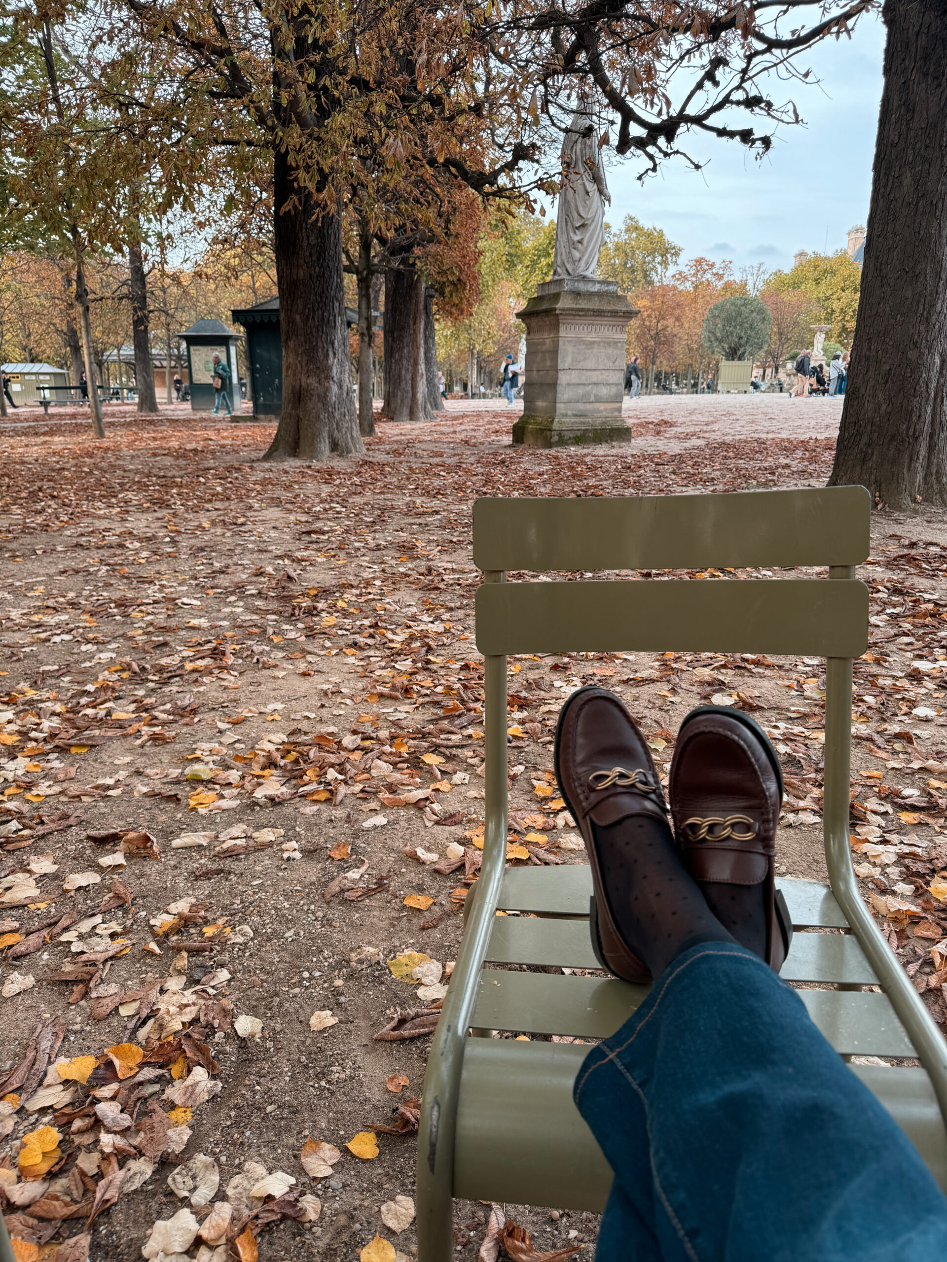 loafers Paris during fall Lady sitting in green chair with loafers on another chair in a park in Paris during fall.