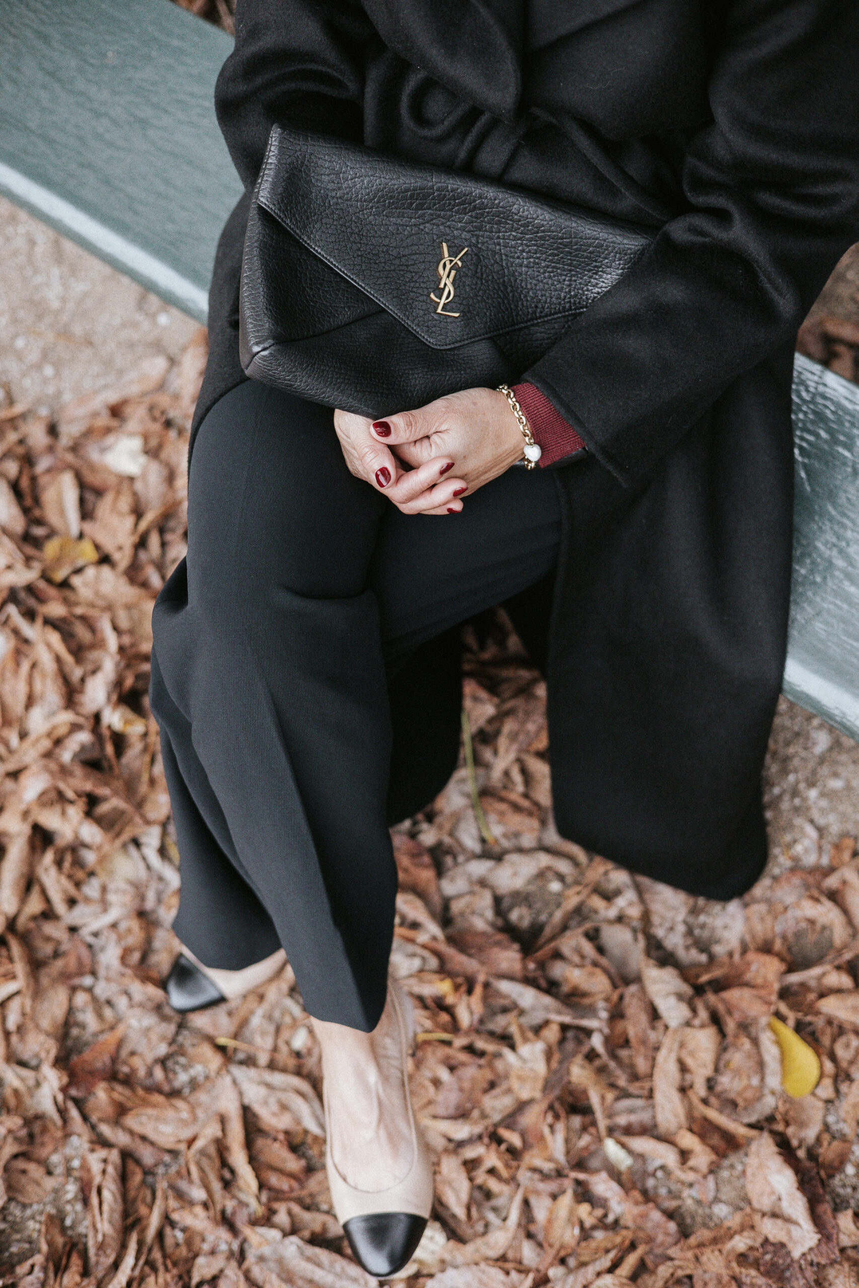 Woman sitting in Luxembroug Gardens in black pants and slingbacks mastering Parisian style.