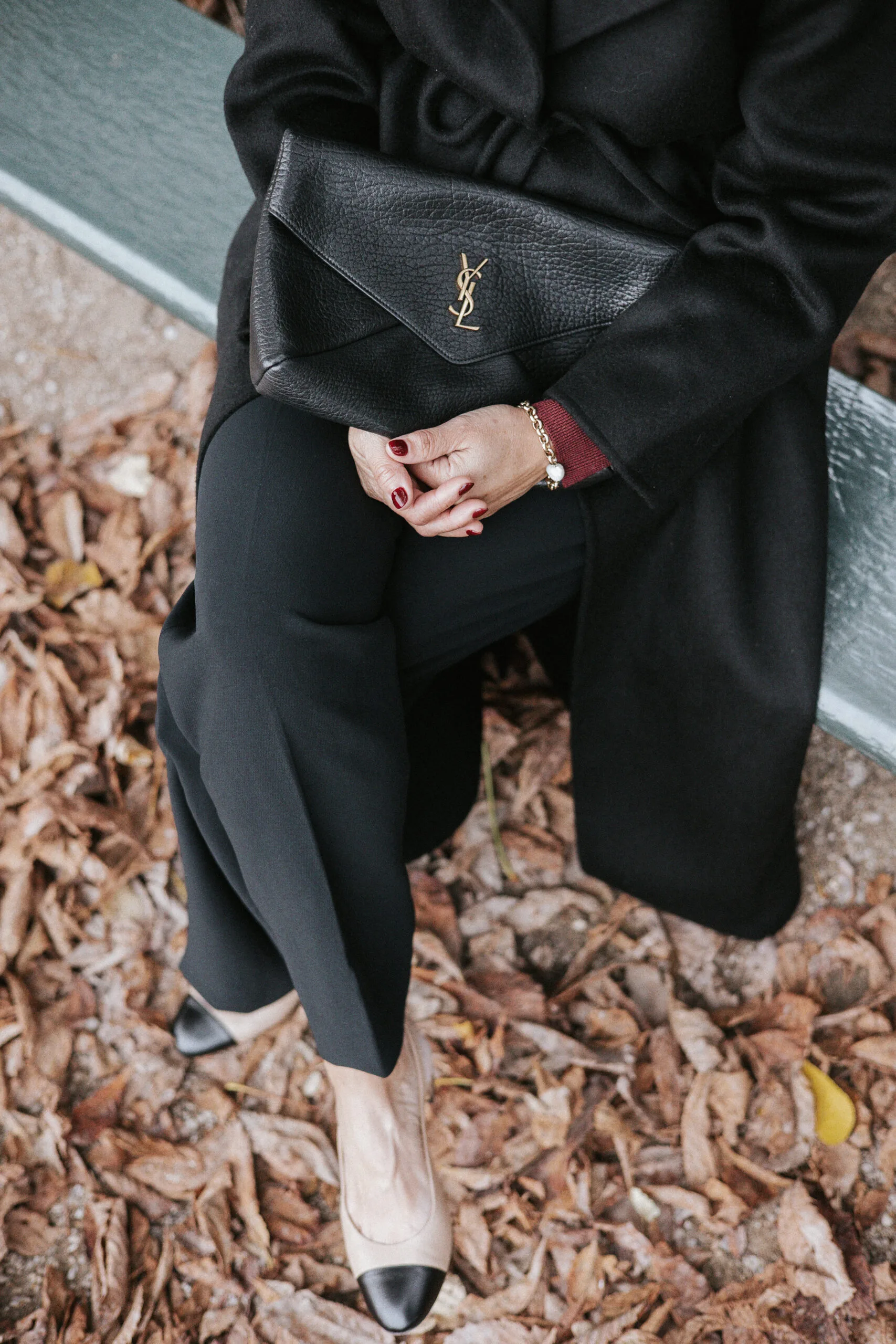 Woman sitting in Luxembroug Gardens in black pants and slingbacks mastering Parisian style.