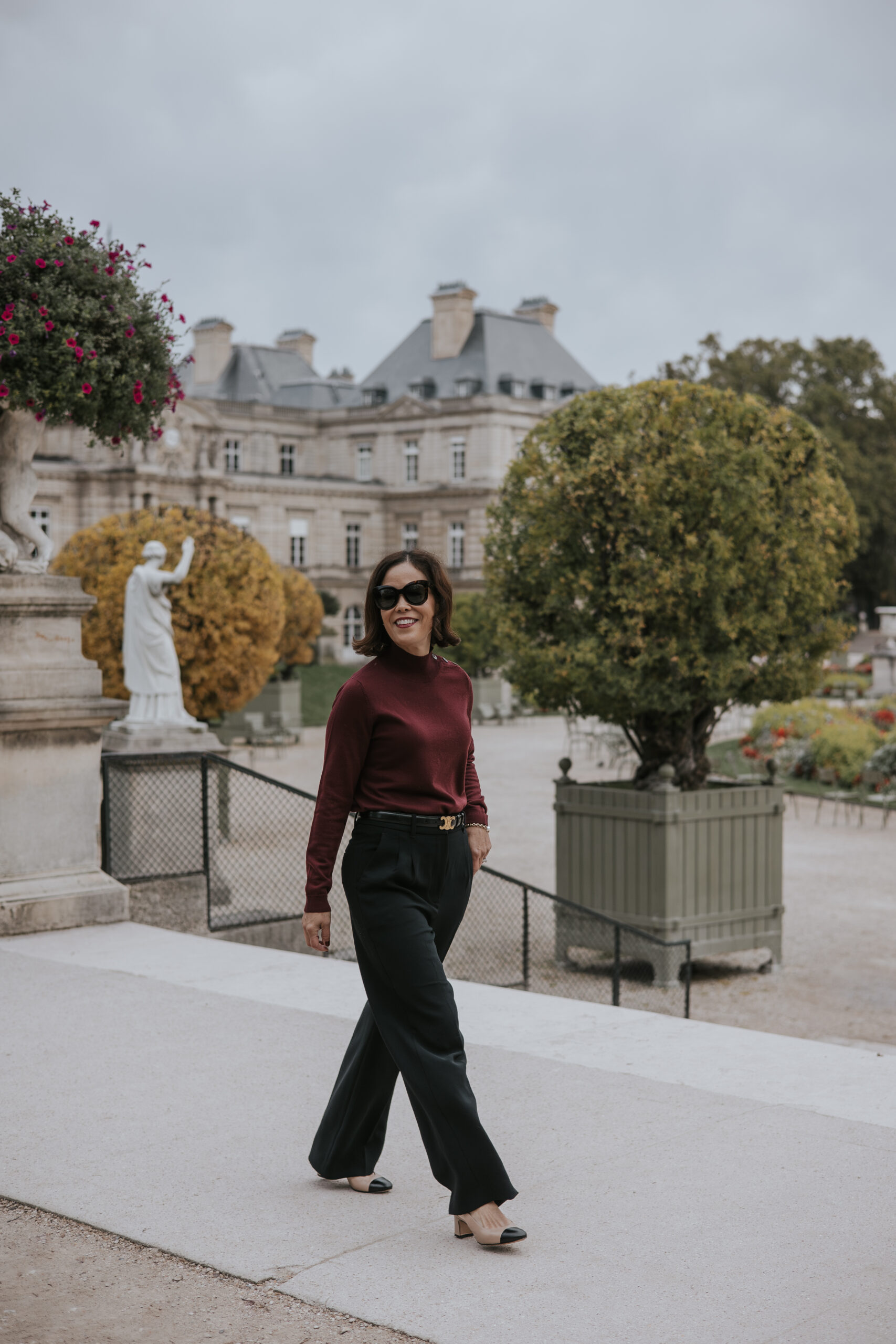 Woman wearing black trousers with burgundy turtleneck and boots.