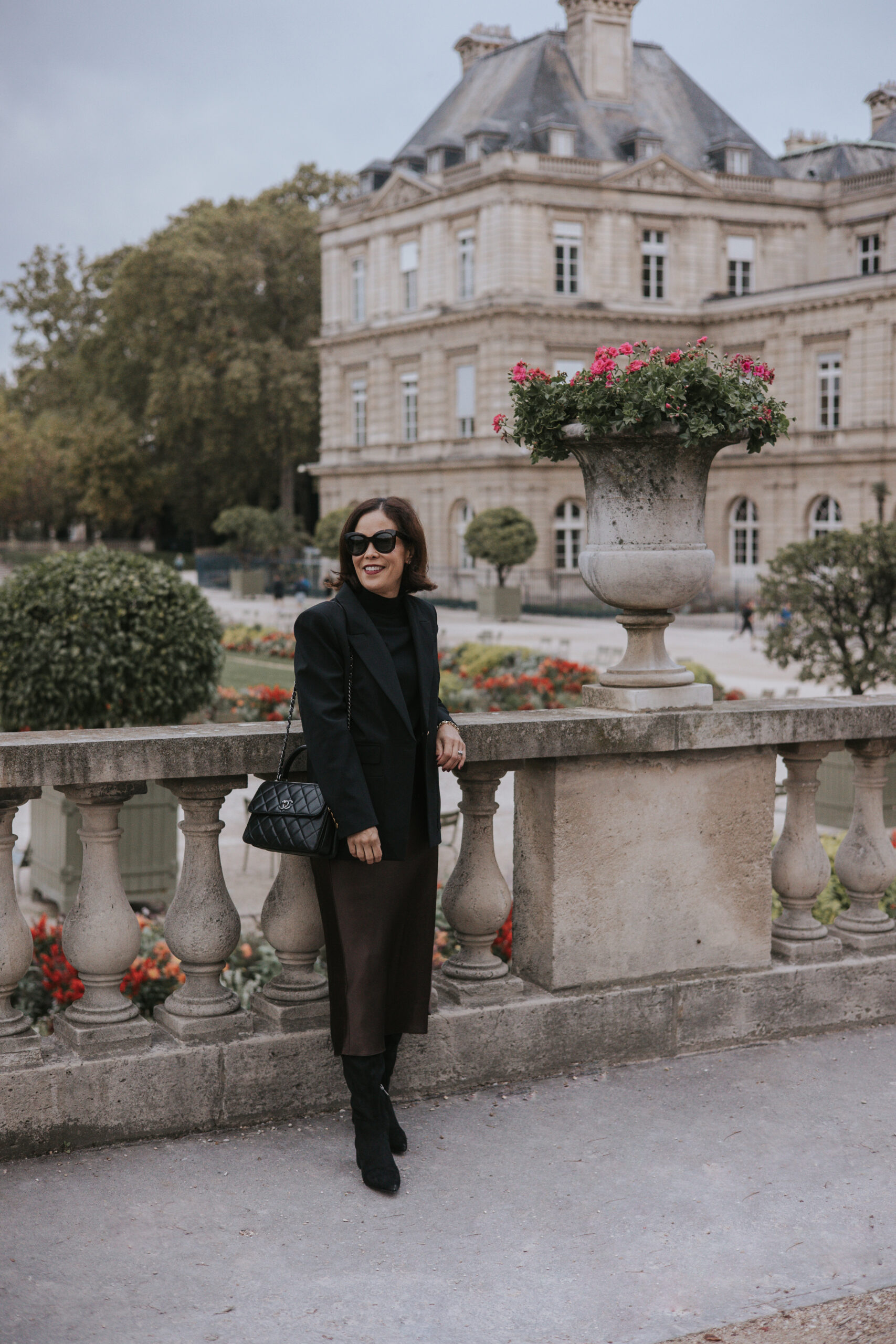 Woman wearing skirt with black blazer and tall boots in Paris.