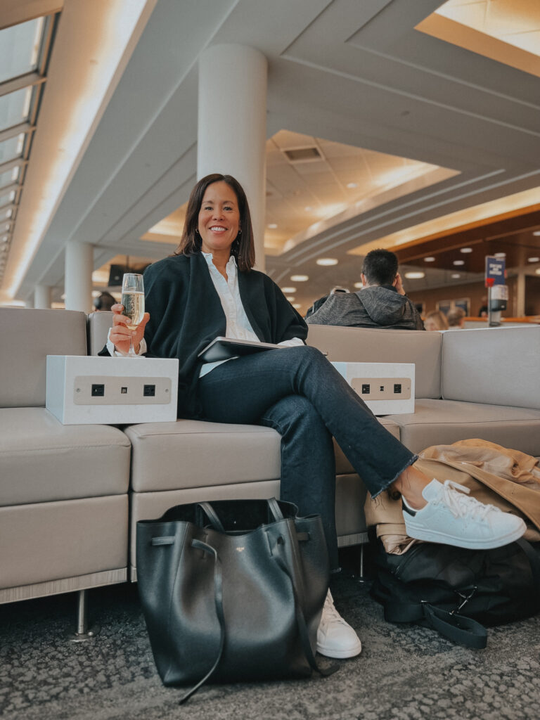 wearing black wrap with denim, sneakers, in an airport lounge.