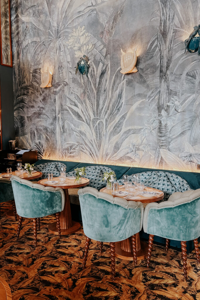 Interior of Cafe Laperouse in Paris with blue velvet chairs and wallpaper.