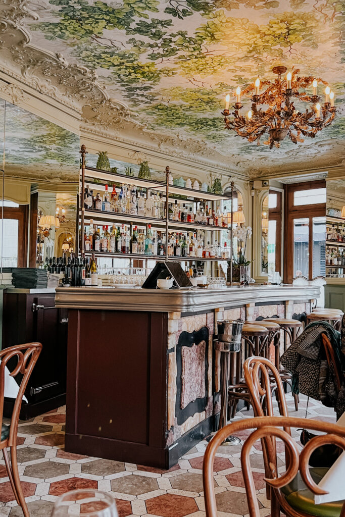 Inside bar with green moulding on ceiling and wood marble on the bartop at where to eat in Paris.
