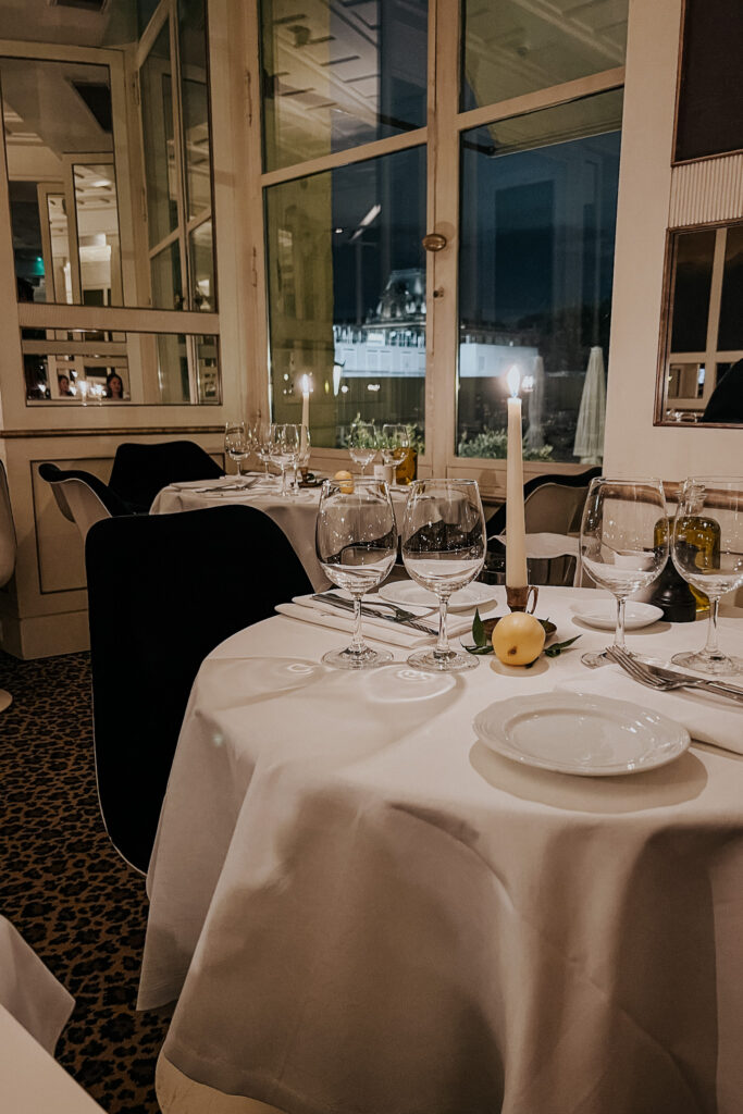 Lit candle sitting on top of a table with white tablecloth and lemon on the table.
