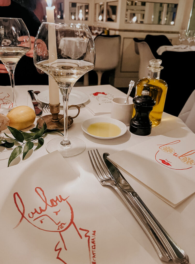 Lou Lou  menu on a table with wine glass and oil in a dish.