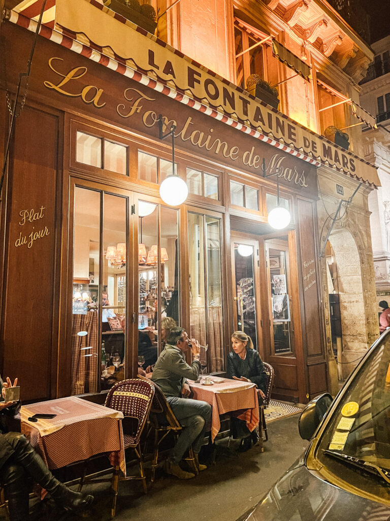 Outside exterior of La Fontaine de Mars in Paris with two people sitting on the terrace.