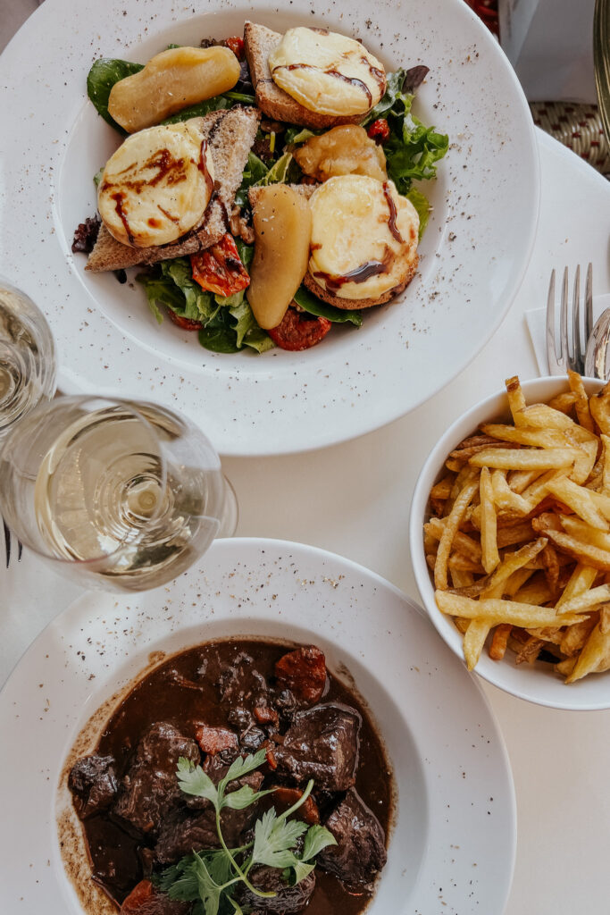 Goat cheese salad and Beef Bourginion on a table in Paris.