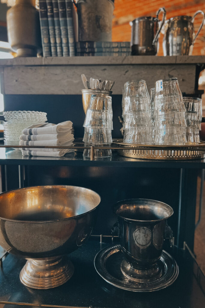 Glasses sitting on a gold bar cart with french kitchen towels, champagne bucket.
