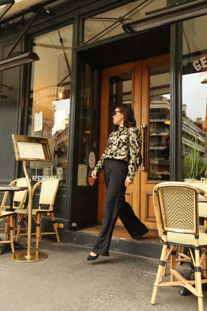 Woman wearing black pants and gold and black top for chic holiday look.