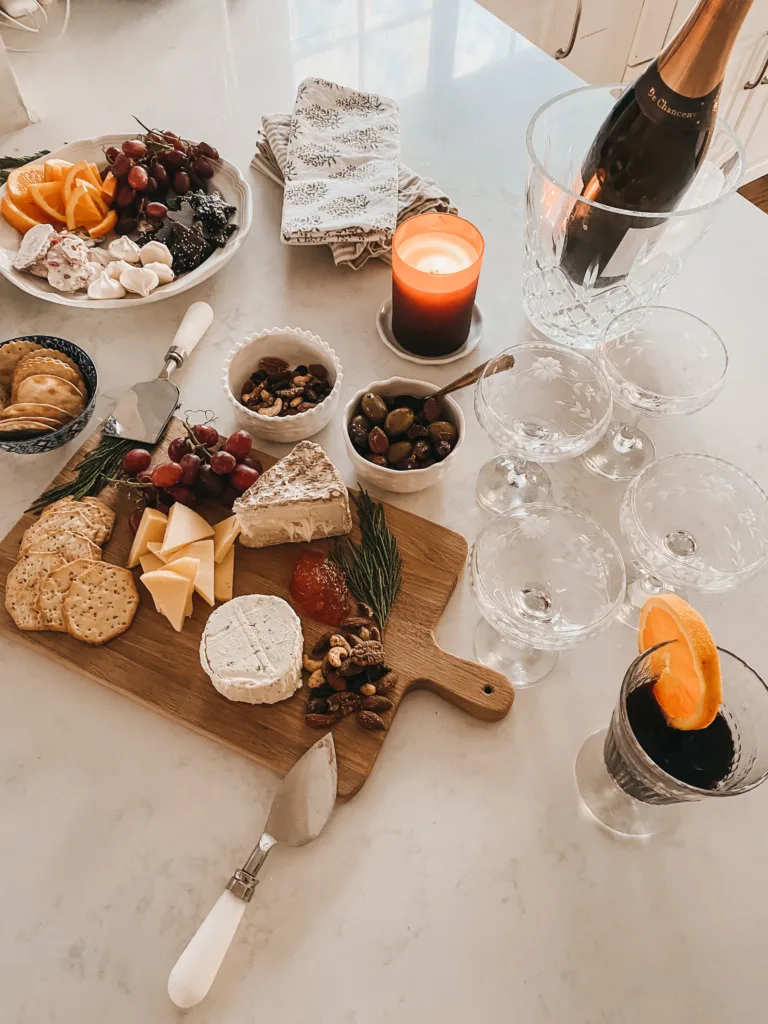 Cheese board sitting on a counter with champagne, different cheeses and crackers